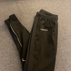 Bagheera träningsbyxor  - Snygga svarta träningsbyxor med reflexdetaljer och förstärkta knän från Bagheera  Vadderade/tjockare på framsidan så perfekta på höst/vinter. Storlek S. 