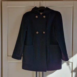 Kappa - Dubbelknäppt jacka/kappa till ungdom eller barn. Kappan har en luva som inte går att att ta av. Lite noppig på framsidan men inget som stör.