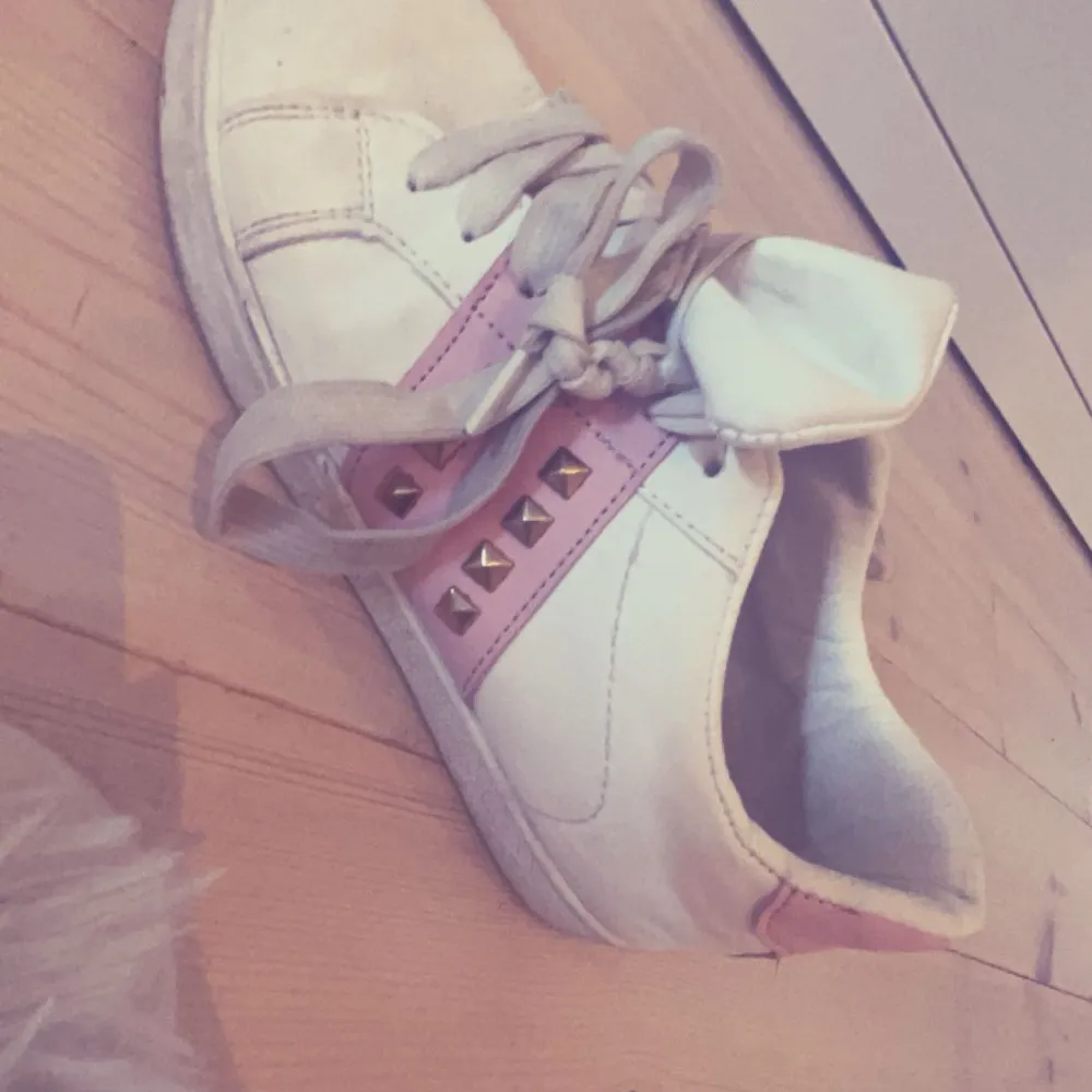 Säljer ett par vita sneakers med rosa detaljer och coola nitar. Skorna har snörning och är perfekta för en avslappnad stil. De är lite använda men fortfarande i bra skick. Perfekta för vår och sommar!🎀🎀🎀storlek 37/38. Skor.