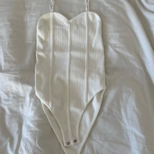 Vit body - Vit ribbad body med knäppning. Använd ett fåtal gånger men i mycket bra skick. Står ingen storlek men passar xs/s