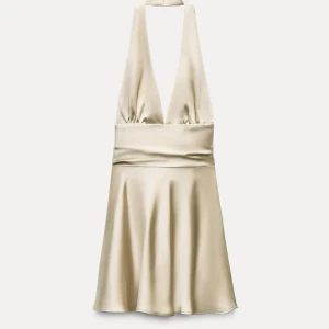 Halterneck klänning i satin - I mycket fint skick, stel Xs funkar på S. Färgen är beige, tyget är satin. Urringad framtill med öppen rygg där man knyter band runt. 