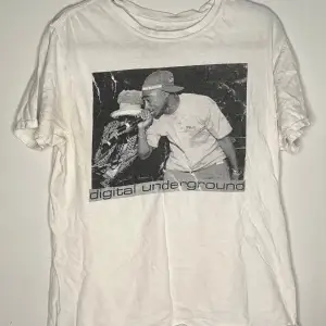 Säljer en vit t-shirt med ett coolt tryck av Digital Underground. Perfekt för dig som gillar retro och musik! T-shirten är kortärmad och har en avslappnad passform. Den är i bra skick och passar perfekt till vardags eller en chill festkväll.