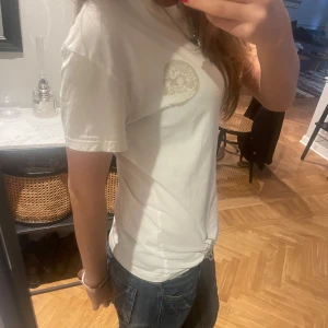 Vit t-shirt med dödskalle från Cheap Monday - Säljer en vit t-shirt från Cheap Monday i storlek S. Den har en cool dödskalletryck på bröstet och är i bra skick. Perfekt för en avslappnad stil eller att bära till vardags.
