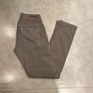 Dondup Chinos - Säljer ett par snygga beige byxor från Ritchie i bra skick. De har en normal passform med knappar och dragkedja framtill. Perfekta för både vardag och fest! 🕺