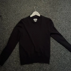 Svart merinoulltröja från These Glory Days - Säljer en stilren svart tröja i merinoull från These Glory Days. Perfekt för både vardag och fest. Tröjan har en klassisk v-ringning och är i mycket bra skick. Supermjuk och bekväm att ha på sig. Passar perfekt till höst och vinter! Köpt från Volt för 900kr. Säljer pga för liten.