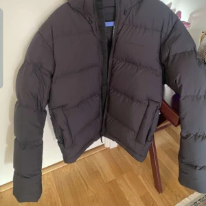 Svart dunjacka från Peak Performance - Säljer en svart dunjacka från Peak Performance i storlek XXL. Jackan är helt ny  och har en stilren design med dragkedja framtill. Perfekt för kalla vinterdagar och håller dig varm och bekväm. Passar både till vardags och mer aktiva dagar. 🖤