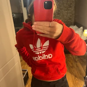 Röd hoodie från Adidas - Säljer en snygg röd hoodie från Adidas, den är i jätte bra skick och är aldrig använd. Hoodien har långa armar och en rak passform.