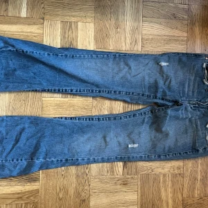 Blå jeans från True Religion - Säljer ett par blå jeans från True Religion i bra skick. De har en klassisk femficksdesign med slitna detaljer för en cool look. Jeansen är tillverkade i Hong Kong och har en bootcut-stil som ger en avslappnad passform. Perfekta för vardagsbruk! Kontakta gärna innan köp. 