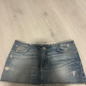 Jeanskjol från Pull&Bear - Säljer en snygg jeanskjol från Pull&Bear i storlek S. Kjolen har en klassisk blå denimfärg med slitna detaljer och fransig nederkant för en cool, avslappnad look. Perfekt för sommardagar eller en casual utekväll. 🕶️
