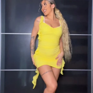 Gul topp och kjol/klänning | OANVÄND  - Säljer en superfin gul topp och kjol som även kan vara en klänning med volangdetaljer på sidorna. Den är ärmlös och har en tight passform som framhäver figuren. Perfekt för sommarens fester eller en utekväll. Klänningen är kort och gjord i ett mjukt, stretchigt material som är bekvämt att bära. Passar S och M. 