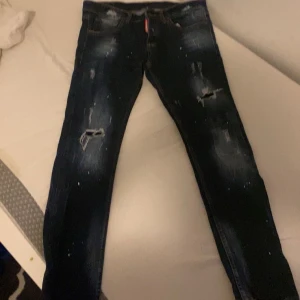 Mörkblå jeans med slitningar  - Säljer ett par mörkblå jeans med coola slitningar på knäna. De har en slim passform och är perfekta för en avslappnad stil. Jeansen har en klassisk femficksdesign och en snygg tvättad look. Perfekta för både vardag och fest!