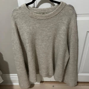 Beige stickad tröja från Gina Tricot  - Mysig beige stickad tröja från Gina Tricot i bra skick. Perfekt för kyliga höst- och vinterdagar. Tröjan har en avslappnad passform med långa ärmar och ribbade kanter vid hals, ärmslut och nederkant. Superbekväm och lätt att matcha med allt! 