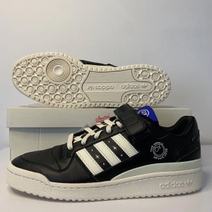 Adidas Forum Low Sneakers - Snygga Adidas Forum Low sneakers i svart och vitt med coola detaljer. Skorna har snörning och kardborreband för extra stil och komfort. Perfekta för både vardag och fest. Helt nya och oanvända, redo att rocka din skosamling!