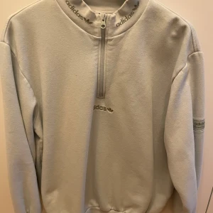 Ljusgrå fleece tröja från Adidas - Säljer en ljusgrön fleece tröja från Adidas. Den har en halv dragkedja och broderad logga på bröstet och ärmen. Använd men det är inget som syns 