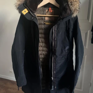 Parajumpers vinterjacka slim fit - Väldigt lätt använd parajumpersjacka. Inga defekter, smuts eller saknade knappar eller liknande. Den har både dubbel dragkedja och knappar. Den har en dragkedja som öppnas i ryggen och 2 fickor samt 2 innerfickor. 