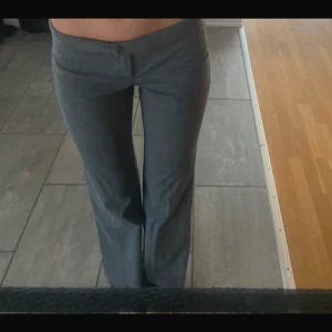 Grå byxor med bootcut - Säljer ett par snygga grå kostymbyxor i från Nelly. De är lågmidjade och har en skön passform som passar perfekt till både vardag och fest. Materialet är mjukt och stretchigt, vilket gör dem bekväma att bära hela dagen. Perfekta för höst och vår!
