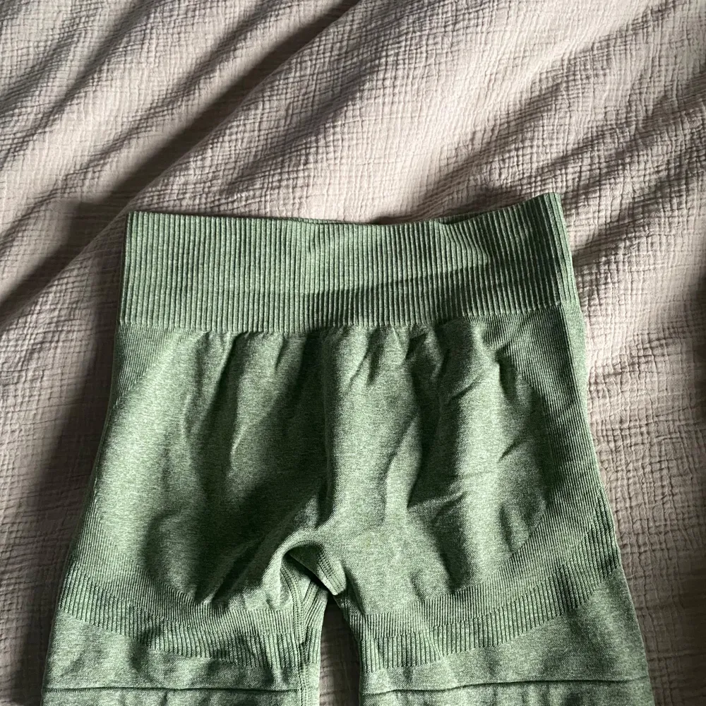 Säljer ett par gröna shorts i ribbat. De är högmidjade och har en bekväm passform med elastisk midja. Perfekta för träning eller en avslappnad dag hemma. De är i mycket bra skick och redo för nya äventyr!. Shorts.