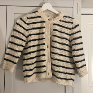 Randig kofta från Zara - Säljer en superfin randig kofta från Zara i beige och svart. Den är stickad och har snygga guldfärgade knappar framtill. Perfekt för höst och vår när du vill ha något mysigt men ändå stilrent. Passar både till vardags och lite finare tillfällen!