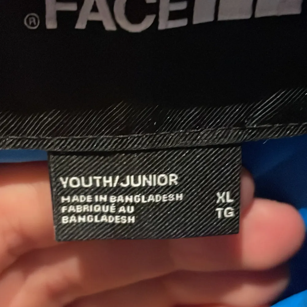 Säljer en snygg blå dunjacka från The North Face i storlek XL för ungdomar. Jackan har svarta detaljer och en dragkedja framtill. Perfekt för kalla dagar med sin varma och bekväma passform. Den har också praktiska fickor med dragkedja. Passar både för vardag och utomhusaktiviteter. Den är i ett mycket bra skick och jag säljer den för ändast 950 då den i nypris går för 2000 på ett ungefär. Hör av för mera bilder eller andra frågor!. Jackor.