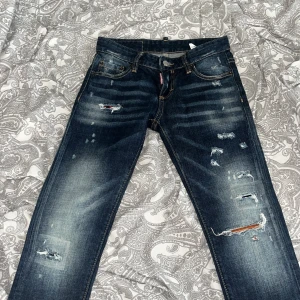 Mörkblå jeans från Dsquared2 - Säljer ett par snygga mörkblå jeans från Dsquared2 i bra skick. De har en cool slitningseffekt och är i en straight stil. Perfekta för en avslappnad look med en touch av edge. Passar bra till både vardag och fest! Det är helt nya 