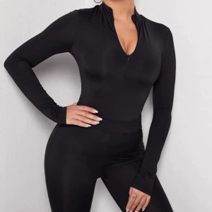 SXY Zip Half Placket Fitted Tee - Säljer en stilren och tight svart sport tröja med lång ärm och kort dragkedja framtill. Perfekt för både träning och vardagsbruk. Materialet är stretchigt och bekvämt, vilket ger en smickrande passform. Passar perfekt för höst och vår! Säljer eftersom jag råkade köpa fel storlek. Helt oanvänd!