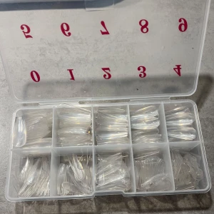 Set med genomskinliga nageltippar i olika storlekar - Ett praktiskt set med genomskinliga nageltippar i tio olika storlekar, perfekt för att skapa egna nageldesigner. Förpackningen är numrerad för enkel användning och organisering. Perfekt för både nybörjare och proffs som vill ha en smidig lösning för nagelförlängning.