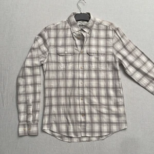 Grå och vit rutig skjorta från Hampton Republic - Säljer en stilren grå och vit rutig skjorta från Hampton Republic i regular fit. Skjortan har långa ärmar och knappar fram samt på kragen. Perfekt för både vardag och lite finare tillfällen. Materialet känns mjukt och bekvämt. Passar bra till jeans eller chinos för en avslappnad look. 