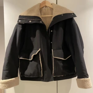 Svart jacka med teddyfoder från & Other Stories - Säljer en svart jacka från & Other Stories i storlek 34. Den har ett mysigt beige teddyfoder och stora fickor med knappar. Perfekt nu till vinter och funkar även under hösten! 🖤