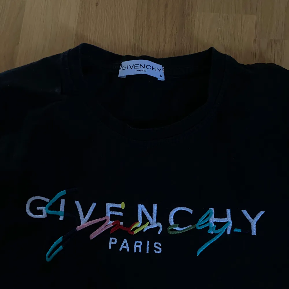 Säljer en svart t-shirt från Givenchy med färgglatt broderat logotyp på framsidan. Bra skick, använd fåtal gånger . T-paidat.