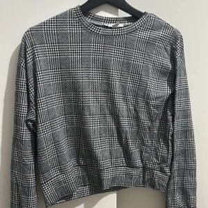 Grå rutig tröja från Amisu - Säljer en snygg grå rutig tröja från Amisu i storlek XS. Den har en klassisk rund hals och långa ärmar, perfekt för både vardag och lite finare tillfällen. Materialet är mjukt och bekvämt, vilket gör den idealisk för höst och vinter. Passar bra med jeans eller kjol för en stilren look.