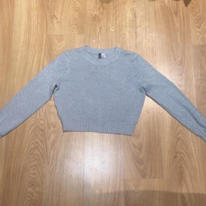 Grå stickad tröja från H&M Divided - Säljer en superfin grå stickad tröja från H&M Divided. Den är croppad och har en normal passform med långa ärmar. Perfekt för höst och vinter, och den är i mycket bra skick. Passar både till vardags och lite mer uppklädda tillfällen. 🩶
