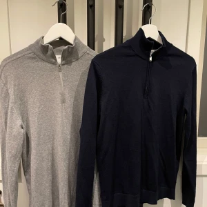 Tröjor med dragkedja från Selected Homme - Två stilrena tröjor från Selected Homme. En grå och en mörkblå, båda med halv dragkedja och hög krage. Perfekta för en avslappnad men snygg look. Gråa size M och blåa S. Superklipp för båda!