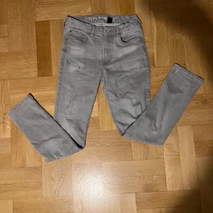 Grå jeansbyxor - Snygga grå jeansbyxor med en slim passform. De har en klassisk femficksdesign och en diskret slitning på framsidan för en trendig look. Perfekta för en stilren vardagsoutfit. Priset kan diskuteras
