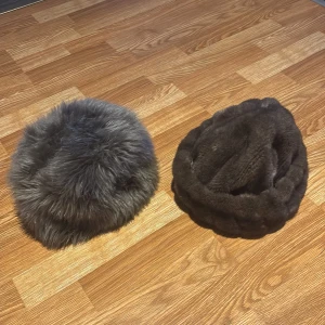 Två pälsmössor i grått och brunt - Säljer två eleganta pälsmössor, en i grått och en i brunt. Den grå mössan har en fluffig yta med en glansig insida, perfekt för kalla dagar. Den bruna mössan har en mjuk och tät pälsstruktur. Båda mössorna är stilrena och håller dig varm under vintern.