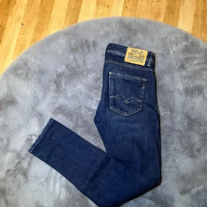 Blå jeans från Replay - Snygga blå jeans från Replay med klassisk femficksdesign och en bekväm passform. Jeansen har en mörk tvätt med lätt slitna detaljer och en knappgylf. Perfekta för en avslappnad stil. Hör av er vid frågor 😁