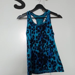 Blå leopardmönstrad linnetopp - Snygg blå linnetopp med leopardmönster. Perfekt för en cool och avslappnad stil. Toppen är ärmlös och har en rund halsringning.