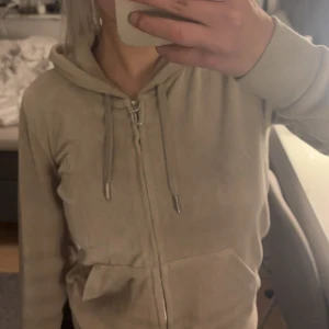 Beige hoodie från Juicy Couture - Säljer en snygg beige hoodie från Juicy Couture i storlek XS. Den har dragkedja och knytband vid huvan, perfekt för en avslappnad stil.