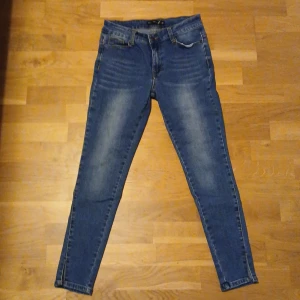 Blå jeans från Black Story - Snygga blå jeans från Black Story i storlek 38. De har en tight passform och är tillverkade i jeansmaterial. Byxorna har en slits vid bensluten och klassiska femficksdetaljer.