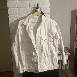 Vit jeansjacka från H&M - Snygg vit jeansjacka från H&M i storlek XS. Jackan har en klassisk design med knappar framtill och två bröstfickor med lock. Perfekt för vår och sommar!