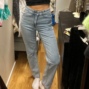 Ljusa jeans från Lindex - Säljer ett par klassiska blå jeans från Lindex i storlek 34. De har en hög midja och en straight passform som ger en tidlös look. Perfekta för en avslappnad stil. Jättefina lite skrynkliga på bilden men dom kommer inte till användning.