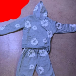 Denim tears - Säljer nu denna fina denim tears tracksuit hoodie med vita blommor. Perfekt för en avslappnad stil. Har en praktisk ficka framtill och en bekväm luva. Perfekt för vintern och höst skick 10/10 