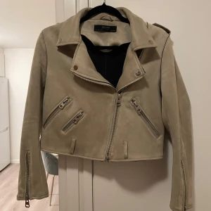 Beige mockajacka från Zara - Snygg beige mockajacka från Zara med dragkedja och flera fickor med dragkedjor. Nypris 869kr, men finns ej kvar i sortiment. Pris kan diskuteras vid snabb affär.