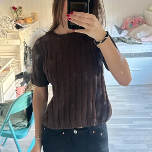 Brun stickad t-shirt - Säljer en snygg brun stickad tröja med korta ärmar. Perfekt för en stilren look. Tröjan har en rund halsringning och är gjord i ett mjukt stickat material, den är super bekväm och passar bra i kallare väder! Den är endast anvönd en gång och är i nyskick☺️