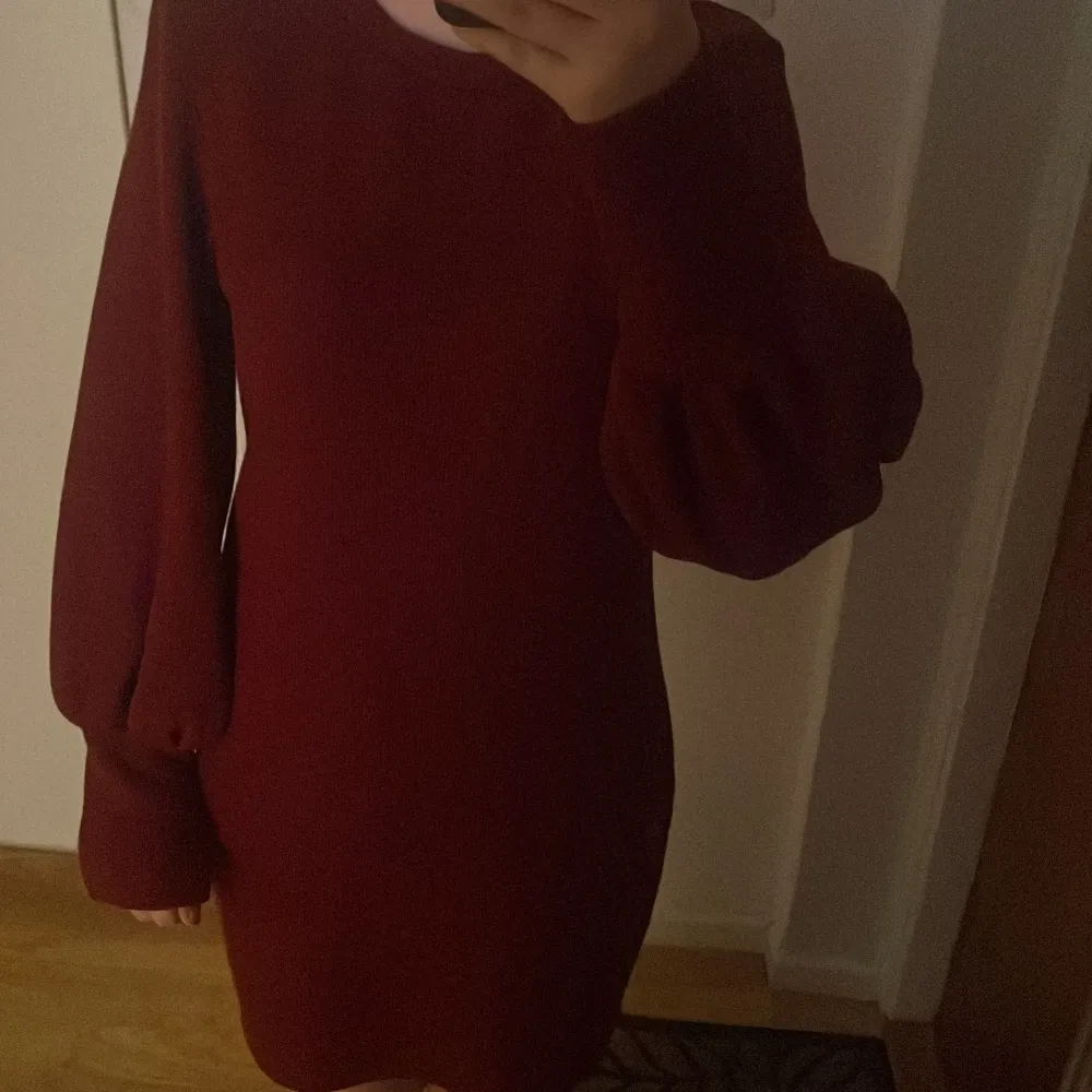 Snygg vinröd klänning med långa ärmar och rund hals. Perfekt för höst och vinter med sin mysiga och stilrena design.. Mekot.