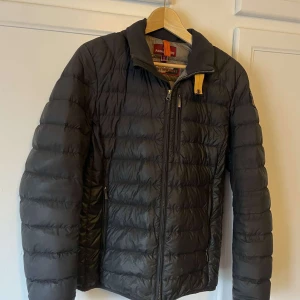 Svart dunjacka från Parajumpers - Säljer en svart dunjacka från Parajumpers med broderad logga på ärmen. Jackan är superlätt och har en dragkedja framtill. Perfekt för kyliga dagar.