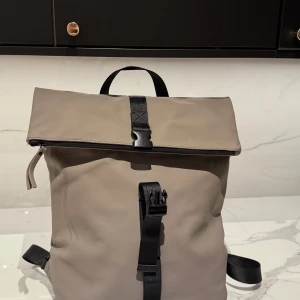 Vattentät ryggsäck  - Snygg och stilren gråbeige ryggsäck med svarta detaljer. Helt ny. Hämtad i Lund eller skickas om köparen står för frakten 😄