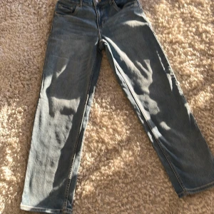 Blå jeans från Levi's - Säljer ett par klassiska blå jeans från Levi's med loose fit. De har en rak passform och är tillverkade i slitstarkt denim. Perfekta för en avslappnad stil.