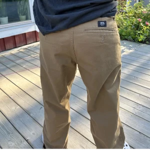 Bruna chinos från Vans - Snygga bruna/beigea chinos från Vans med en klassisk design. De har en dragkedja och knapp framtill. Använda ett fåtal gånger men i toppen skick 🤎