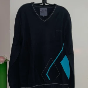 Ny Blå tröja med grafiskt mönster från Blue Print - Säljer en blå tröja från Blue Print med ett coolt grafiskt mönster i turkos och grått. Ny!Tröjan har en v-ringad hals och långa ärmar, perfekt för en stilren look.