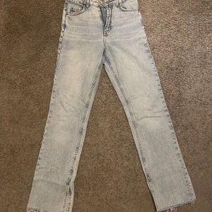 Ljusblå jeans från Gina Tricot  - Säljer ett par ljusblå jeans från Gina Tricot. De har en klassisk design med fickor, slits vid fotändan och knappgylf. Perfekta för en avslappnad stil.